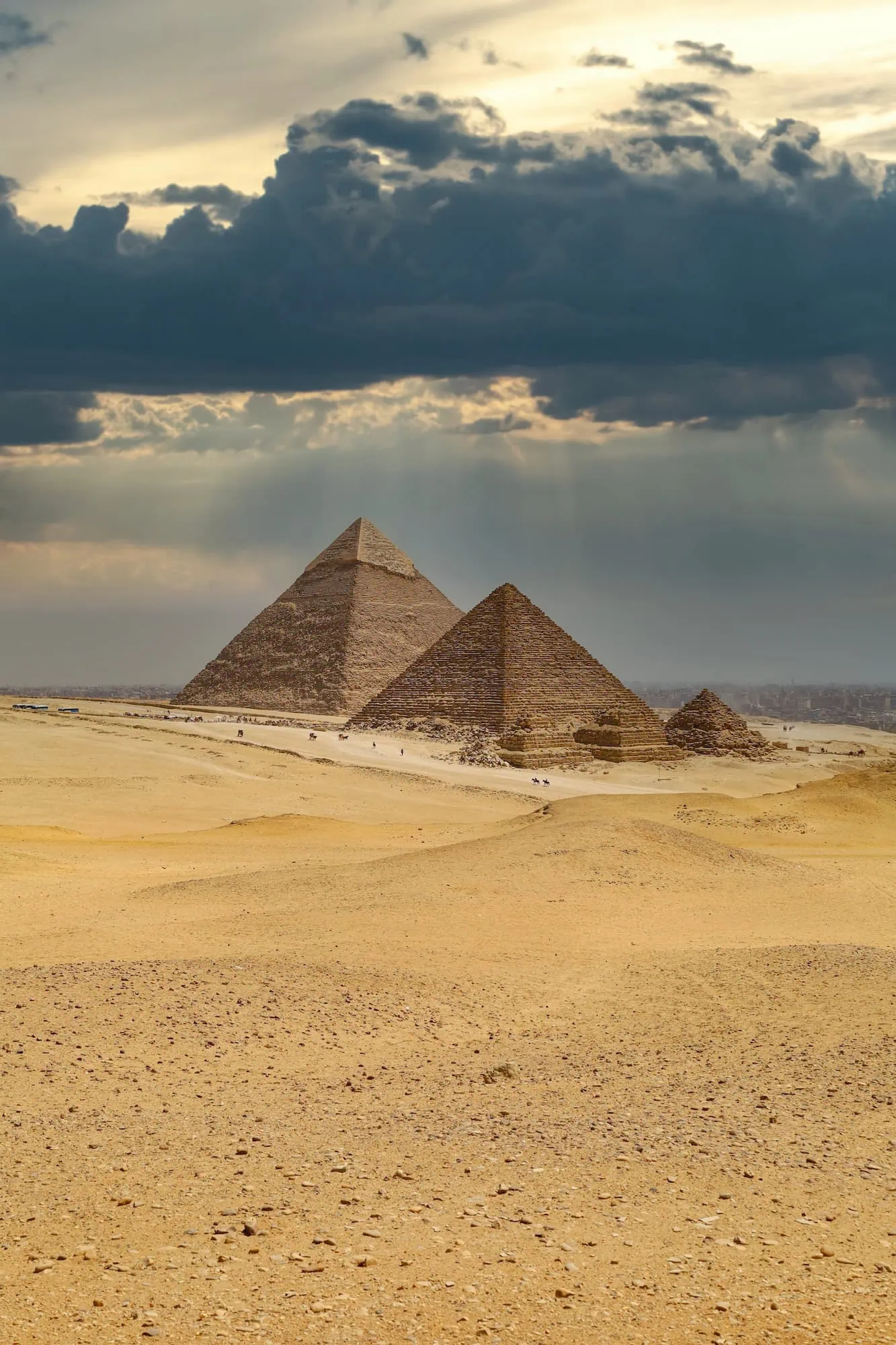 Majestic Pyramids of Giza against clear desert sky with clouds