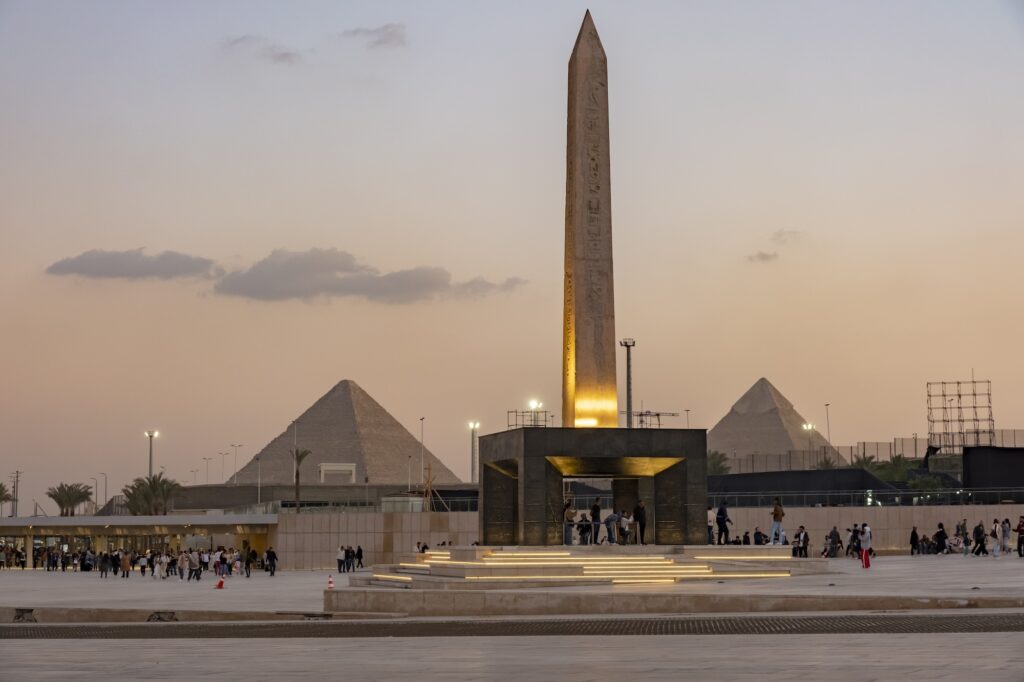 Exterior view of the Grand Egyptian Museum with the ancient obelisk and pyramids at dusk, Grand Egyptian Museum, Giza