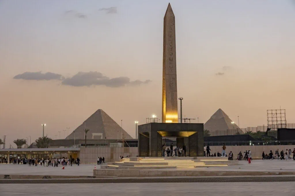 Exterior view of the Grand Egyptian Museum with the ancient obelisk and pyramids at dusk, Grand Egyptian Museum, Giza