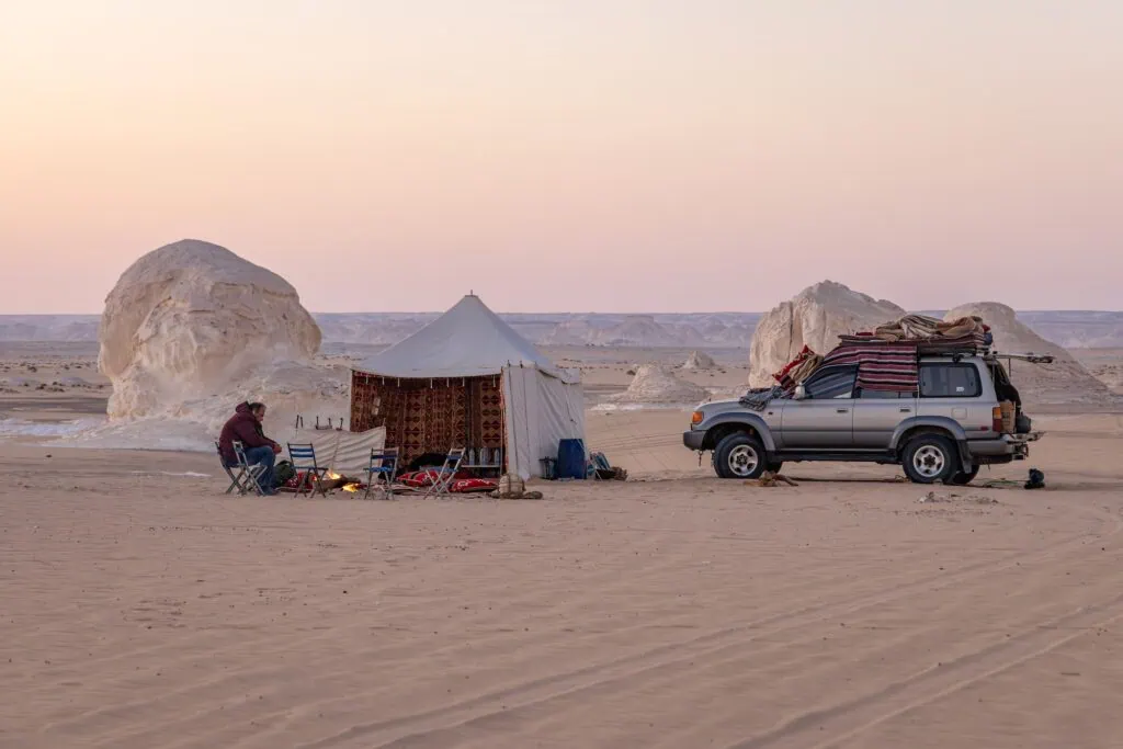 Tourist camp with tents set among white limestone rock formations in White Desert National Park, Al Farafra