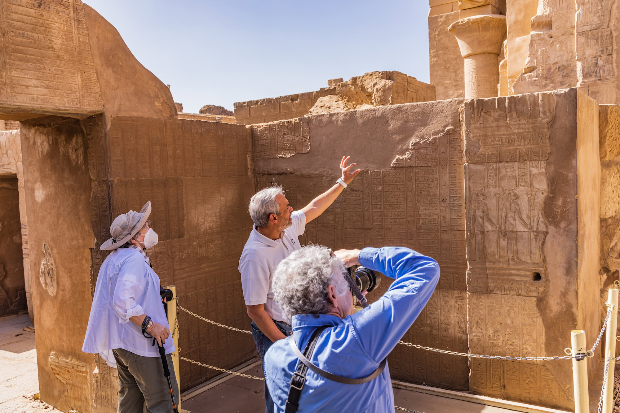 Guide explaining hieroglyphic carvings to tourists at Kom Ombo Temple