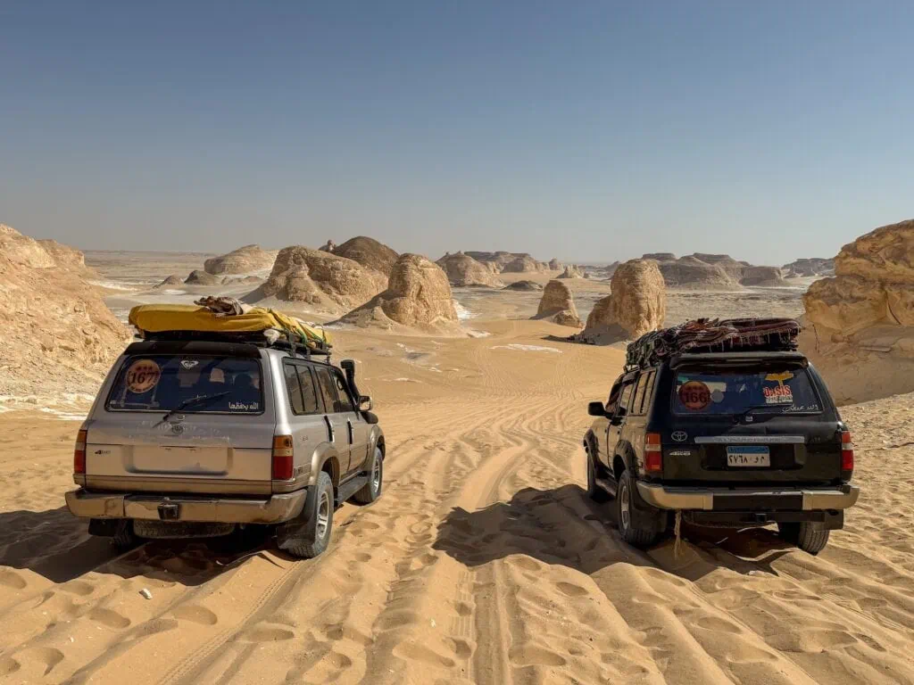 Land Cruiser jeeps driving across sand dunes along the safari route to desert camping, White Desert, Farafra