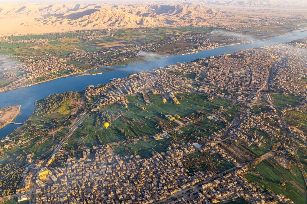 Panoramic view of the Nile River, city buildings, and surrounding farmland seen from a hot air balloon over Luxor, Luxor