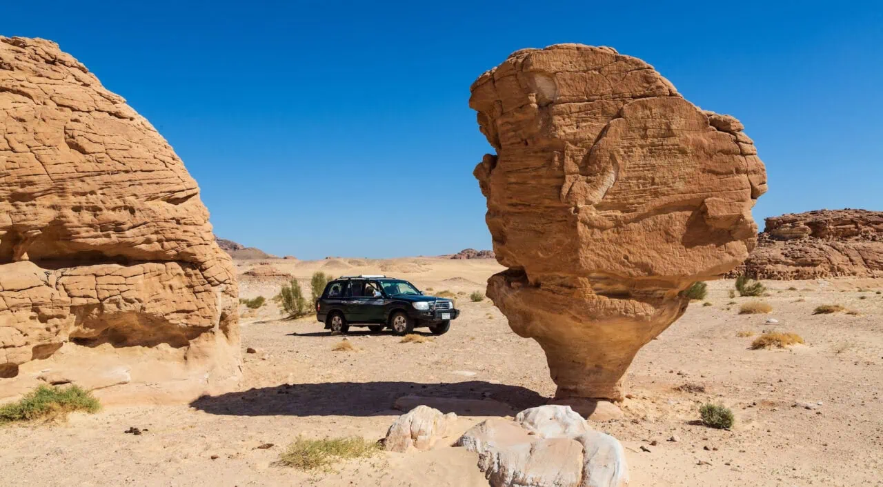 Mushroom Rock formation with a parked vehicle on the desert floor in the Sinai Desert, Nuweiba