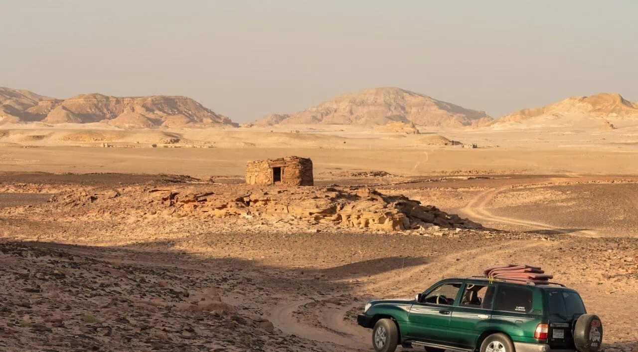 Nawamis stone huts with a desert safari vehicle on sandy terrain in the Sinai Desert, Nuweiba