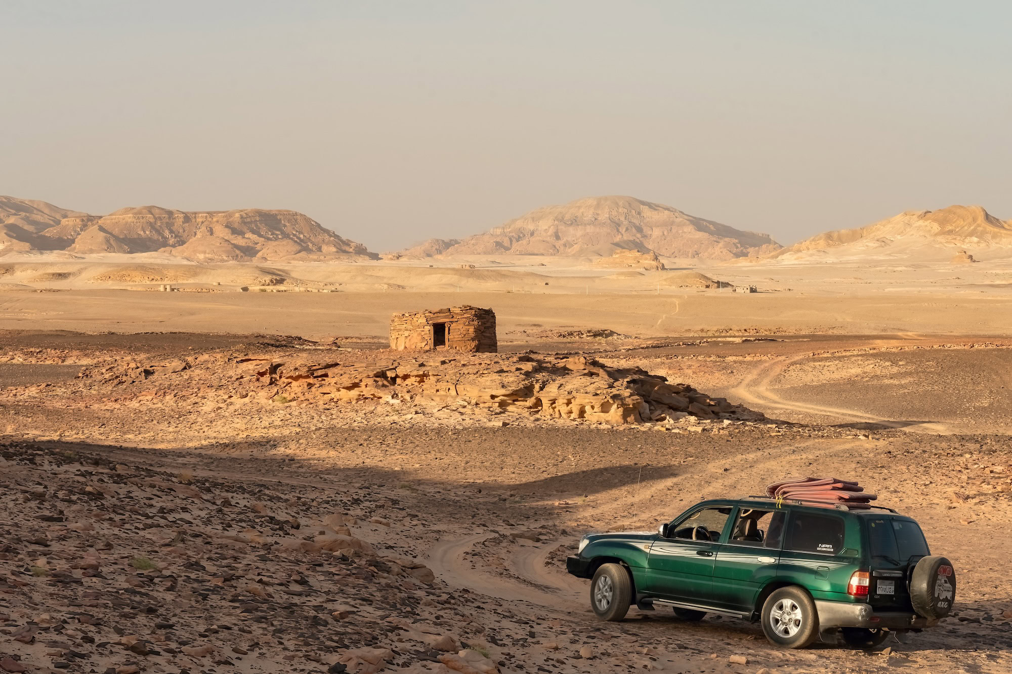Nawamis stone huts with a desert safari vehicle on sandy terrain in the Sinai Desert, Nuweiba