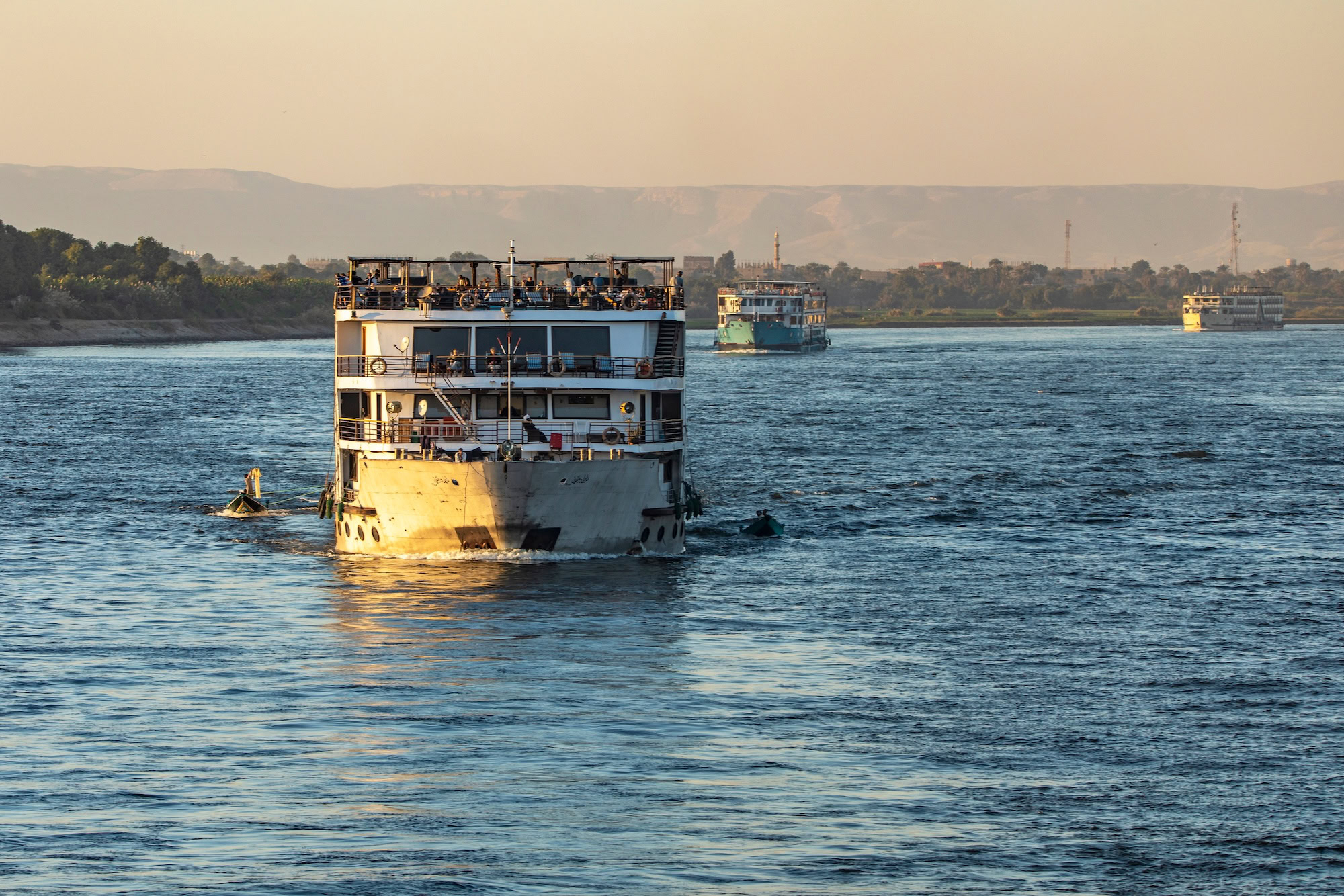 Cruise ships sailing on the Nile River during golden hour with passengers