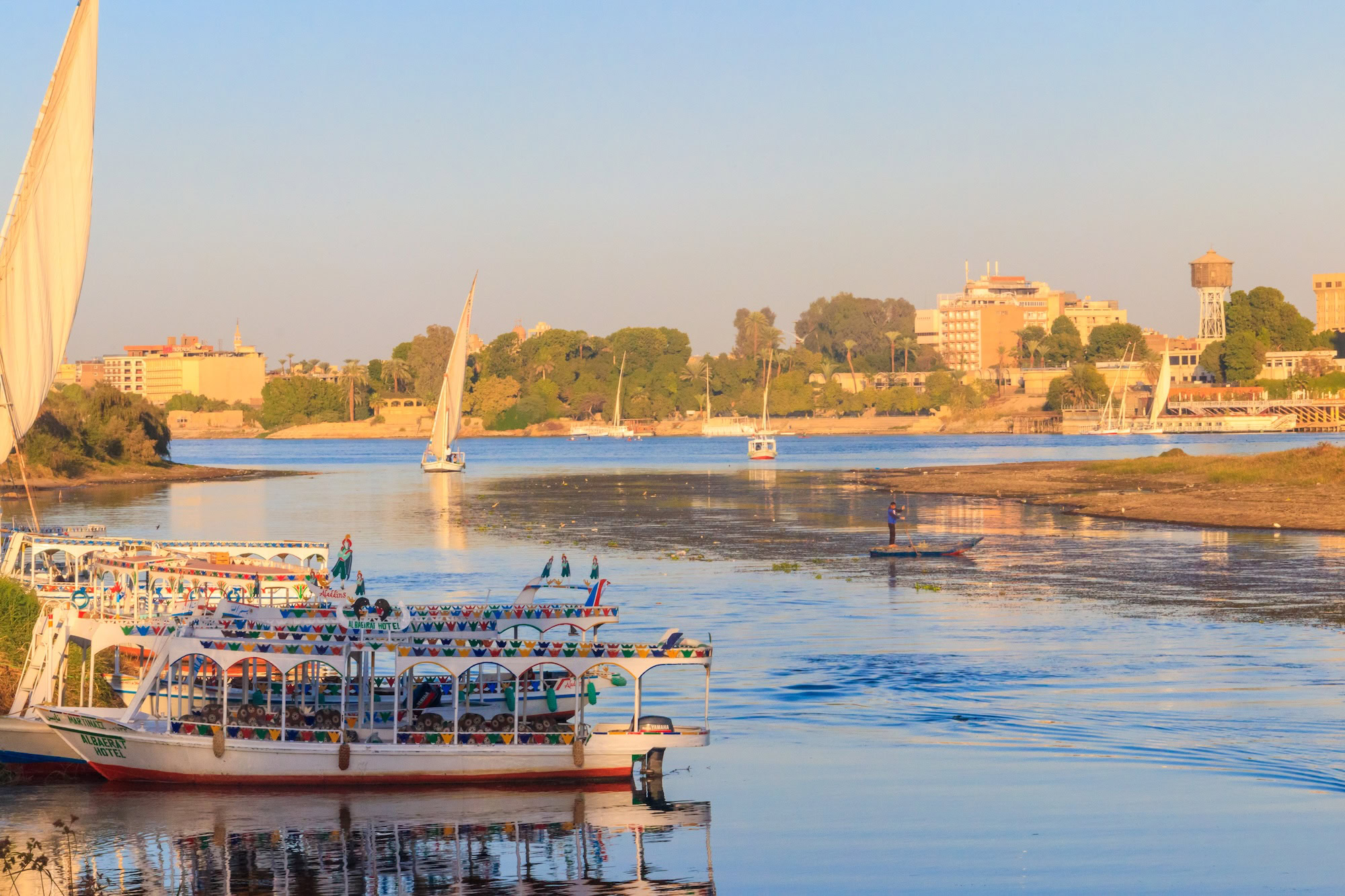 Tourist boats and feluccas moored along the Nile River at sunset in Luxor