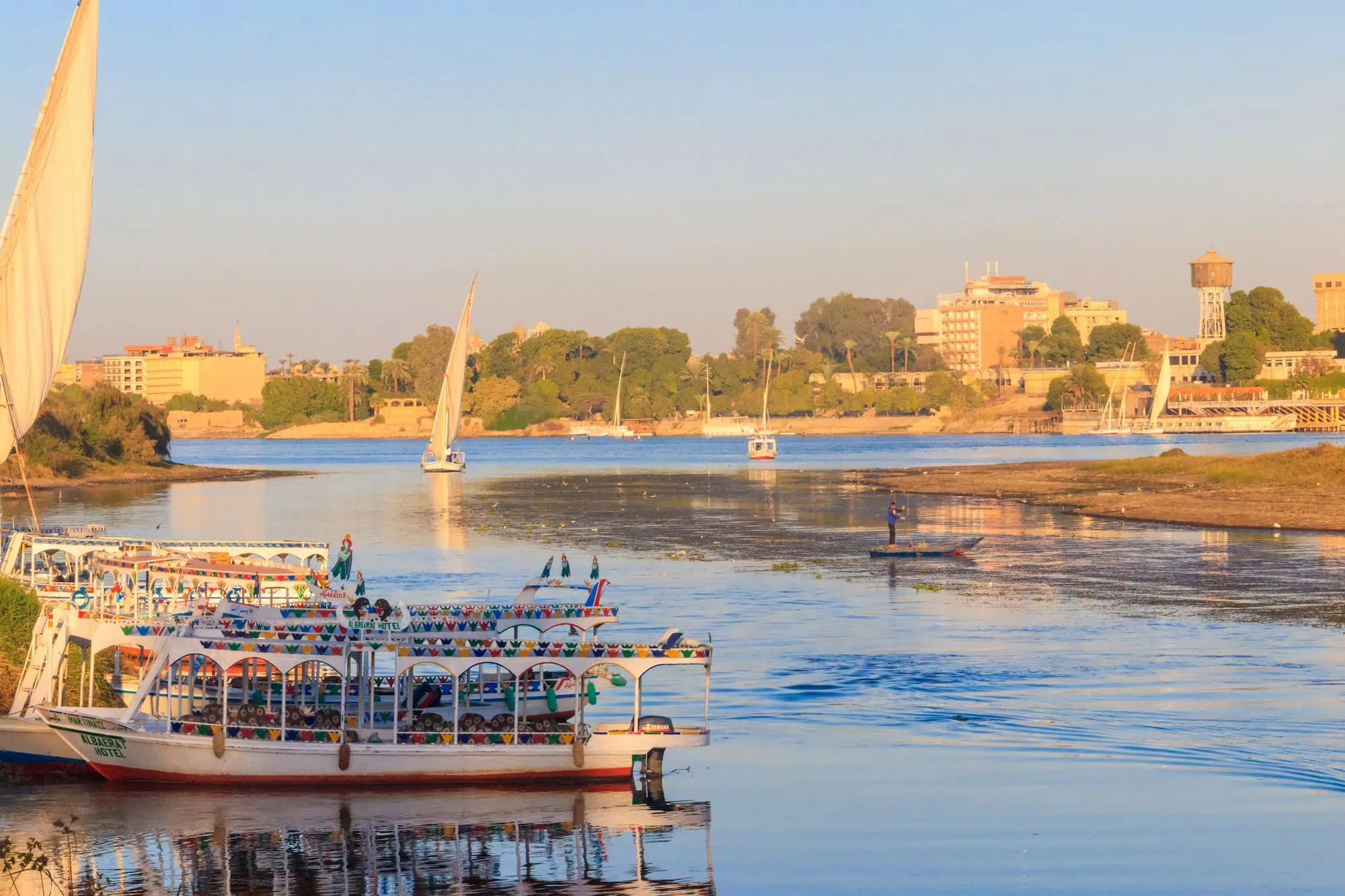 Tourist boats and feluccas moored along the Nile River at sunset in Luxor