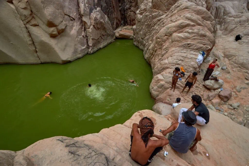 Natural oasis of Wadi El-Weshwash with clear freshwater pools surrounded by rocky desert terrain, South Sinai