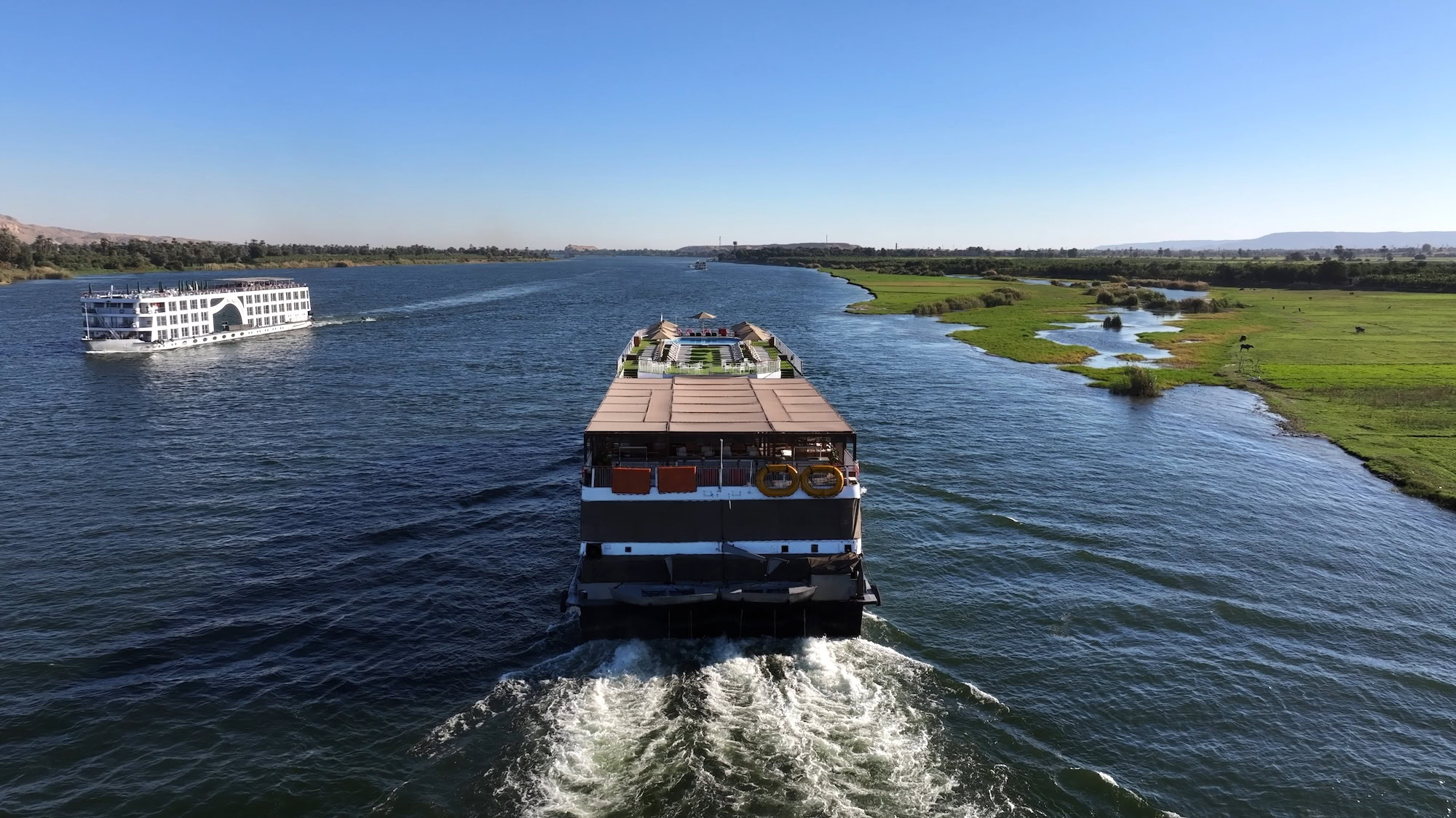 Two Nile cruise ships sailing on river with green fields and islands