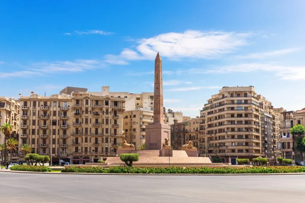 Ramses II obelisk standing in Tahrir Square with surrounding buildings and traffic, Cairo