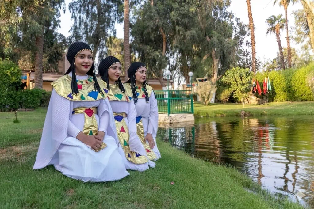 Costumed performers in ancient Egyptian attire kneeling beside a waterway at the Pharaonic Village, Pharaonic Village, Cairo
