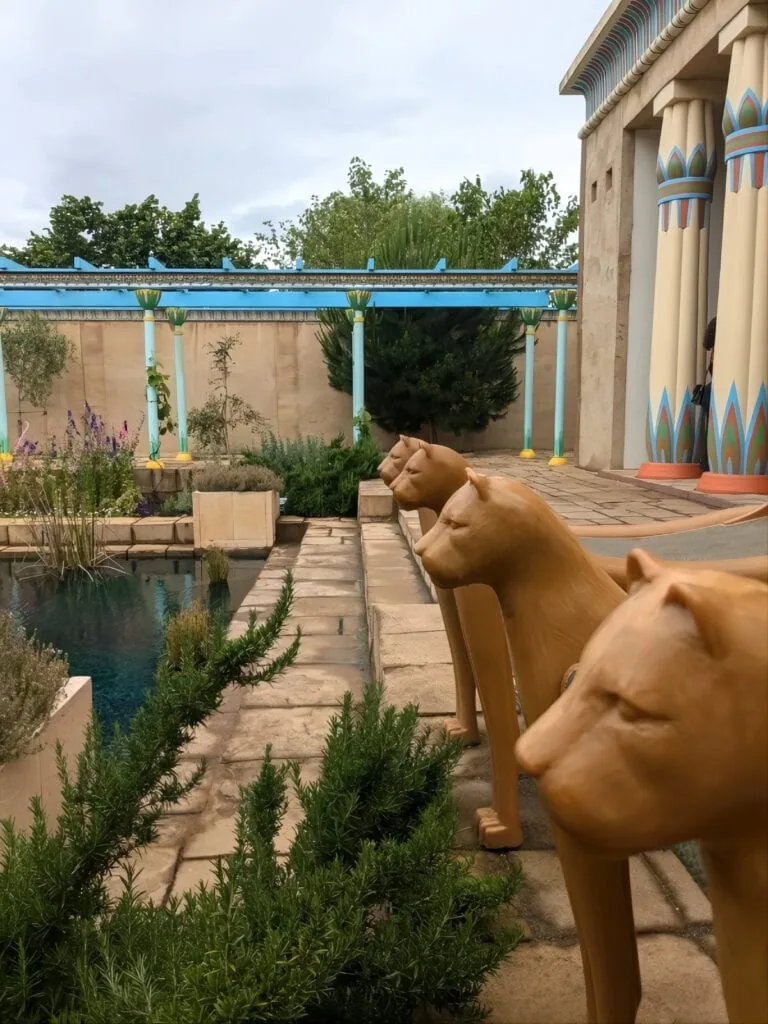 Row of lion statues beside a water channel with a painted columned façade at the Pharaonic Village, Pharaonic Village, Cairo