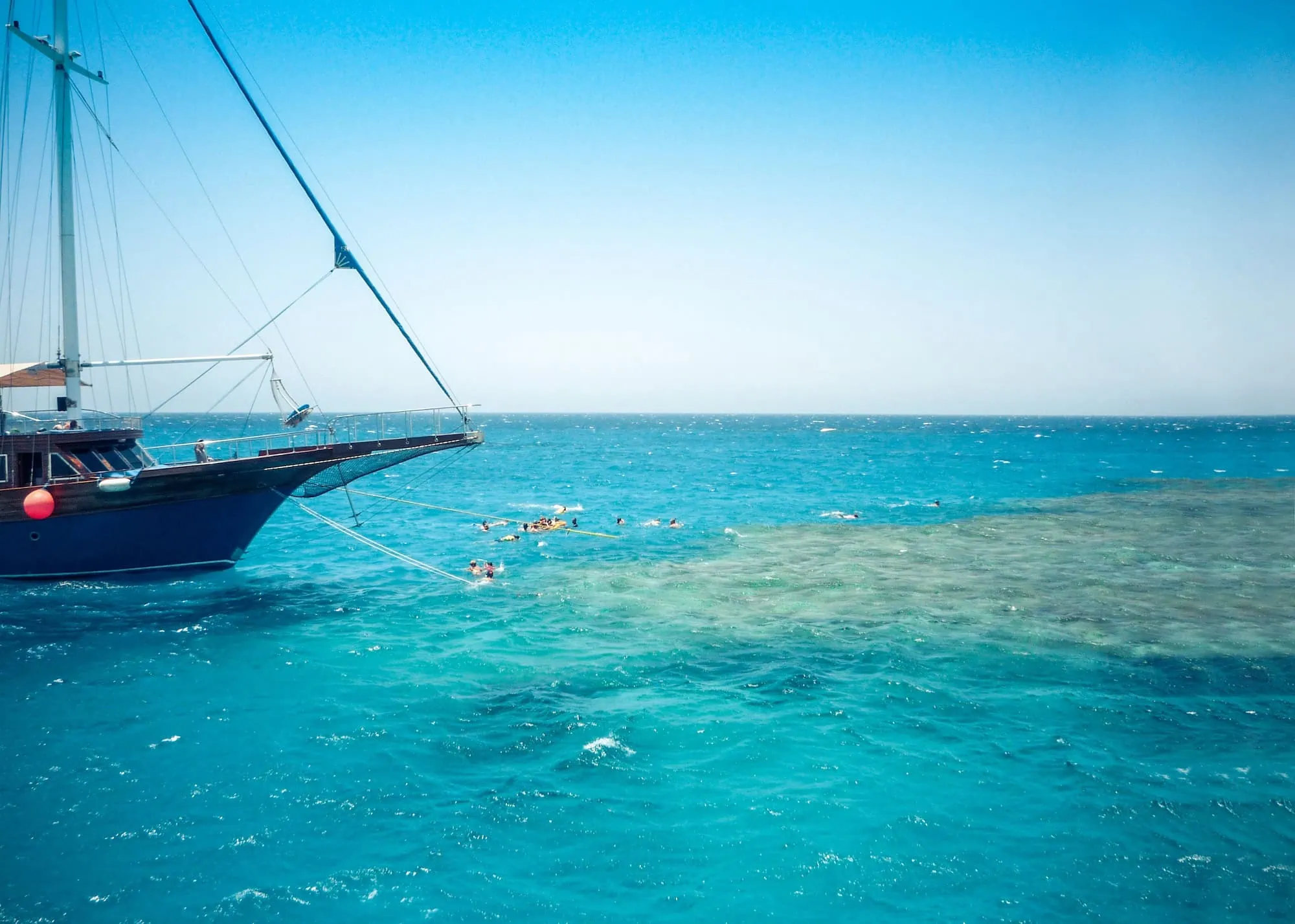 Sailboat with tourists swimming and snorkeling in turquoise Red Sea waters