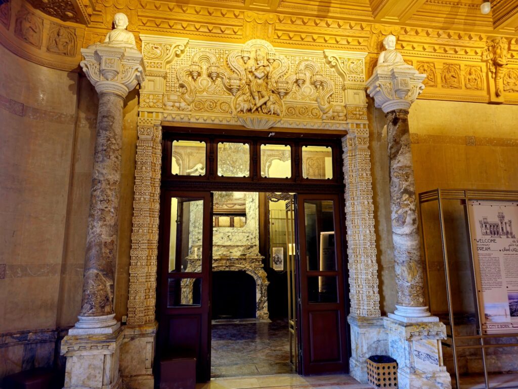 An ornate interior doorway with carved Hindu-style details and marble columns inside the Baron Empain Palace, Cairo