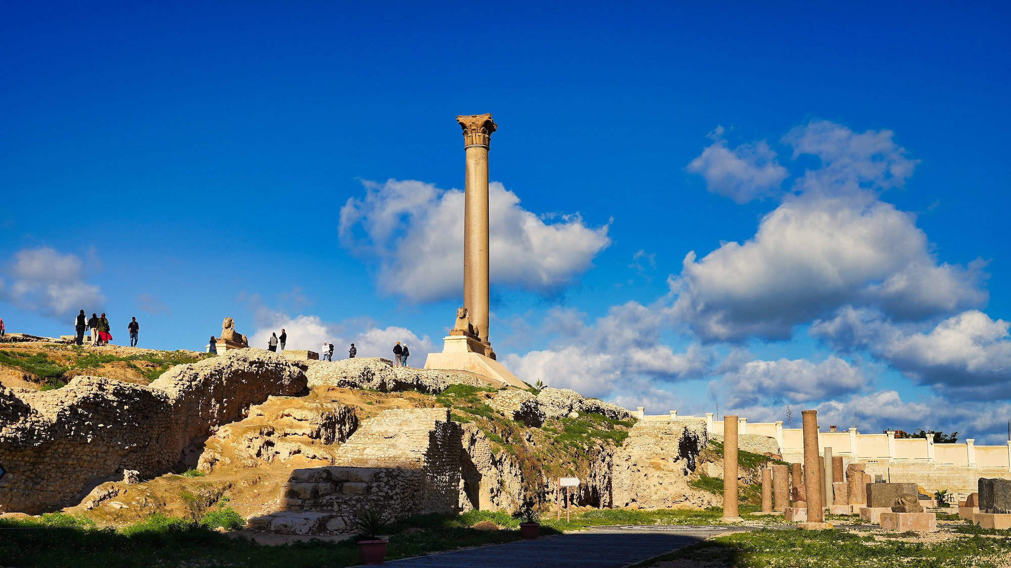 Pompey's Pillar ancient Roman column with tourists exploring archaeological ruins in Alexandria