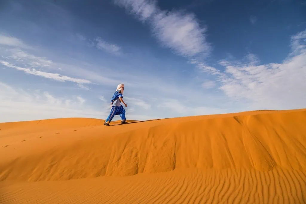 A Berber Man at the edge of the Erg Chebbi with amazing blue sky in Sahara near Merzouga, Morocco