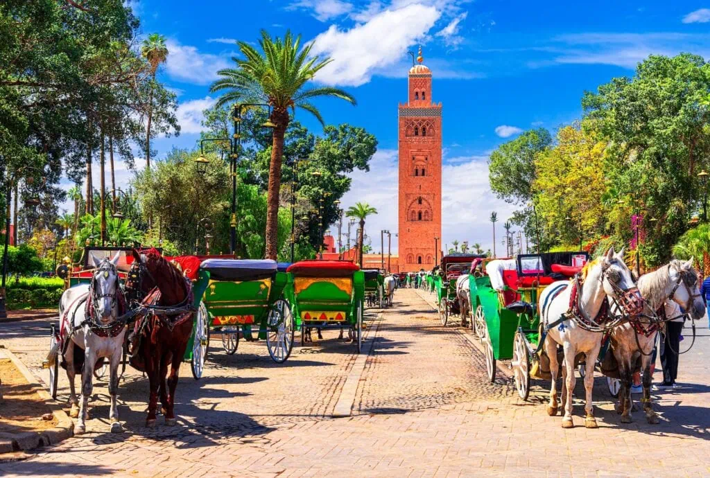 Koutoubia Mosque minaret with horse-drawn carriages in the foreground at Jemaa el Fna square, Marrakesh