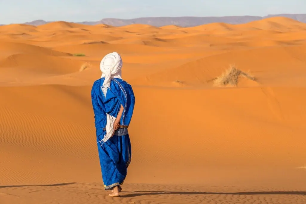 View from behind to Berber in traditional clothing. Erg Chebbi desert, Morocco
