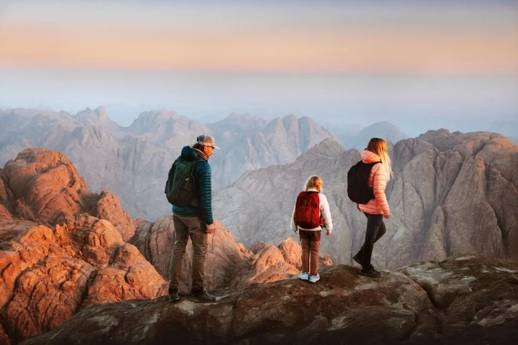 Family hiking along rocky trail on Mount Sinai with desert mountains in the background, Saint Catherine