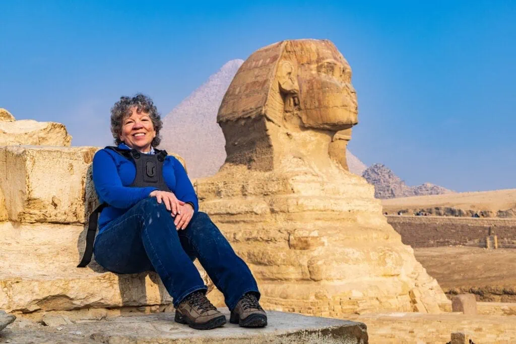 Female tourist in front of the Great Sphinx with the pyramids in the background, Giza