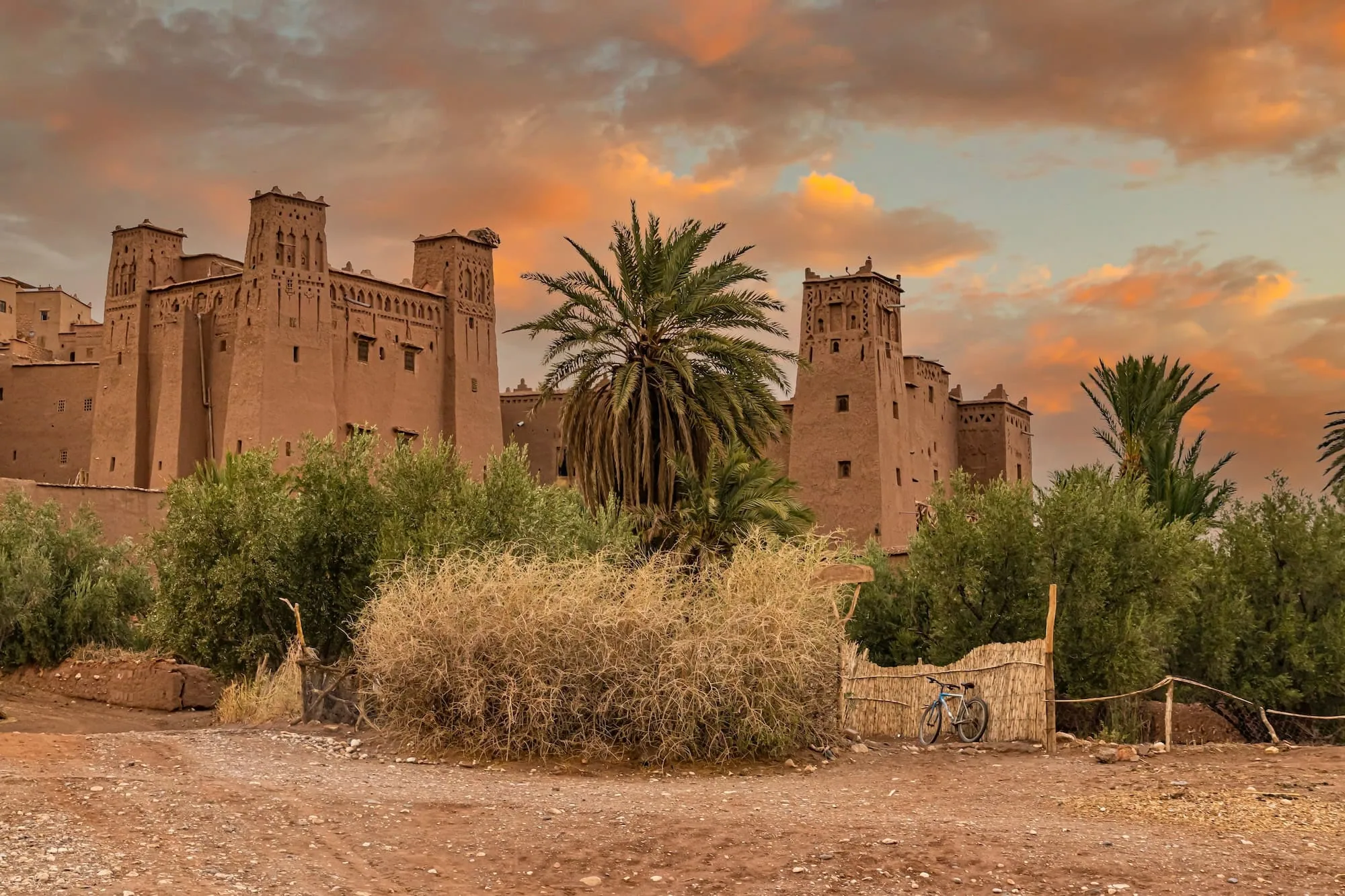 Traditional Berber village with mud-brick kasbah towers in Morocco's Atlas Mountains during golden hour