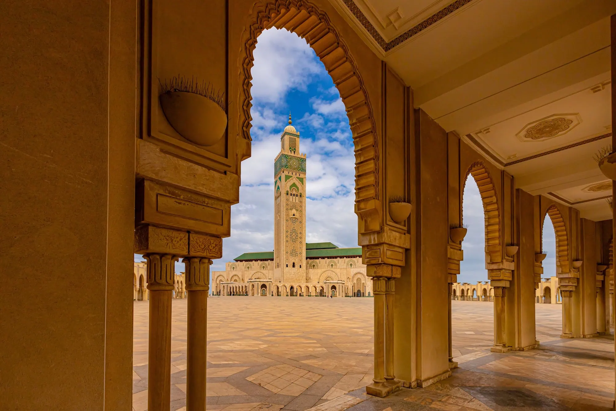 Hassan II Mosque in Casablanca viewed through ornate Islamic arches showing the tall minaret and dome
