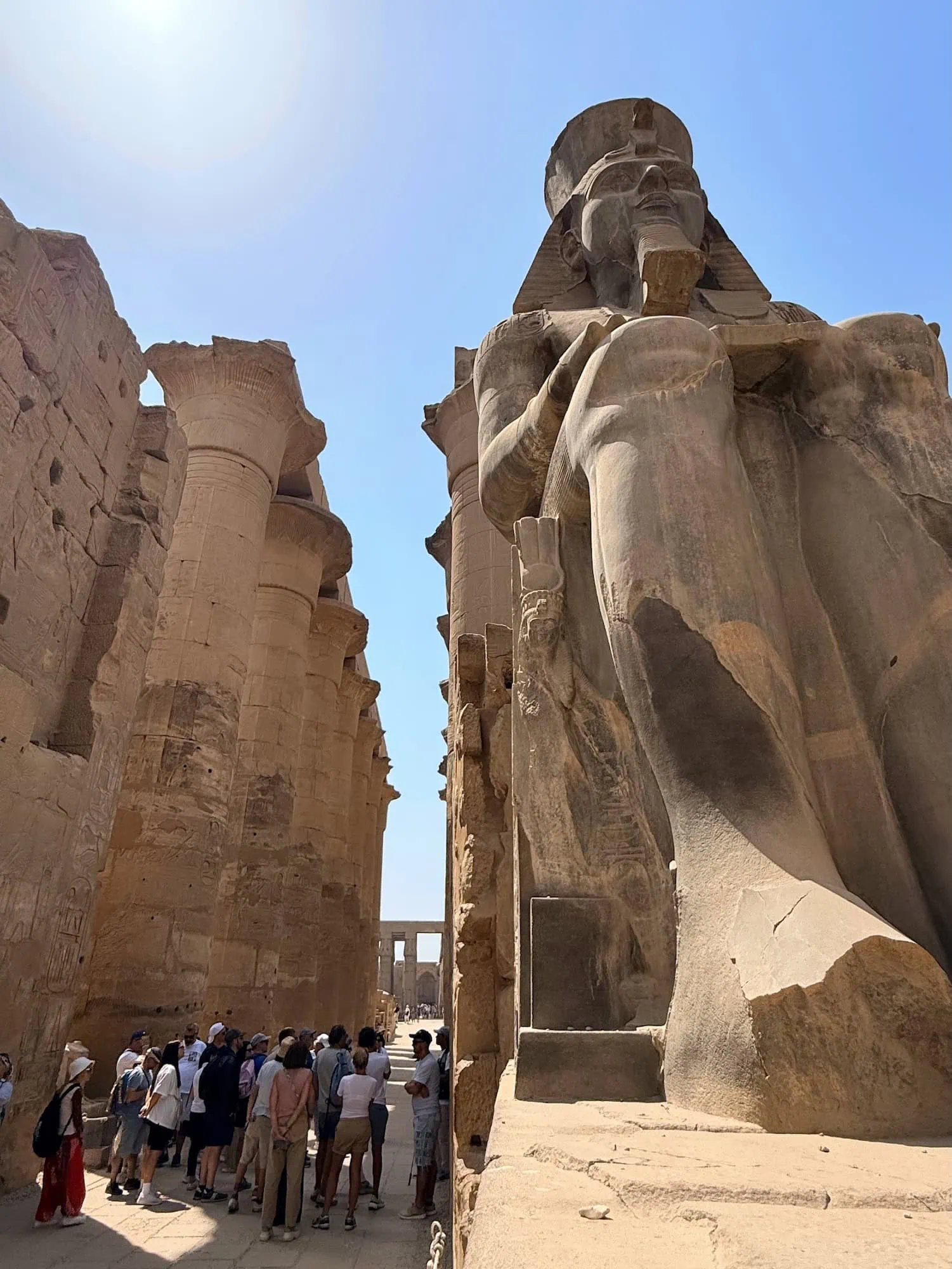 Tourists exploring the ancient stone columns and statues at Luxor Temple in Egypt