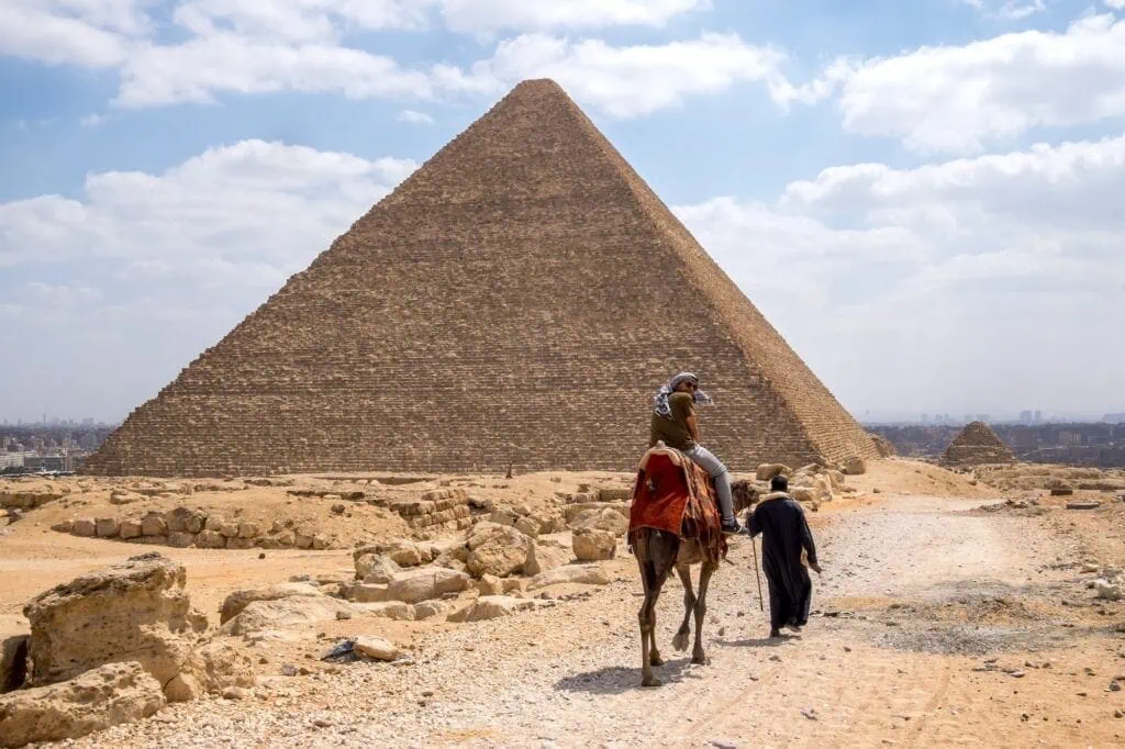 People riding camels in front of the Great Pyramid of Giza