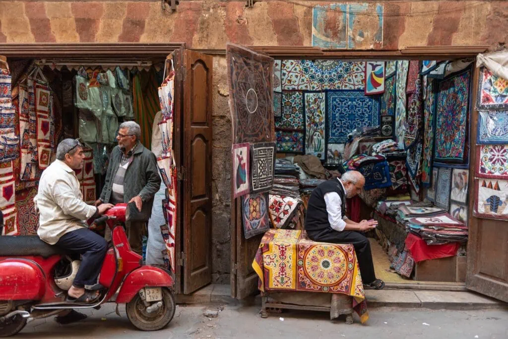 Shops selling Egyptian textiles with patterned fabrics hanging in the Tentmakers Bazaar near Khan El Khalili, Cairo