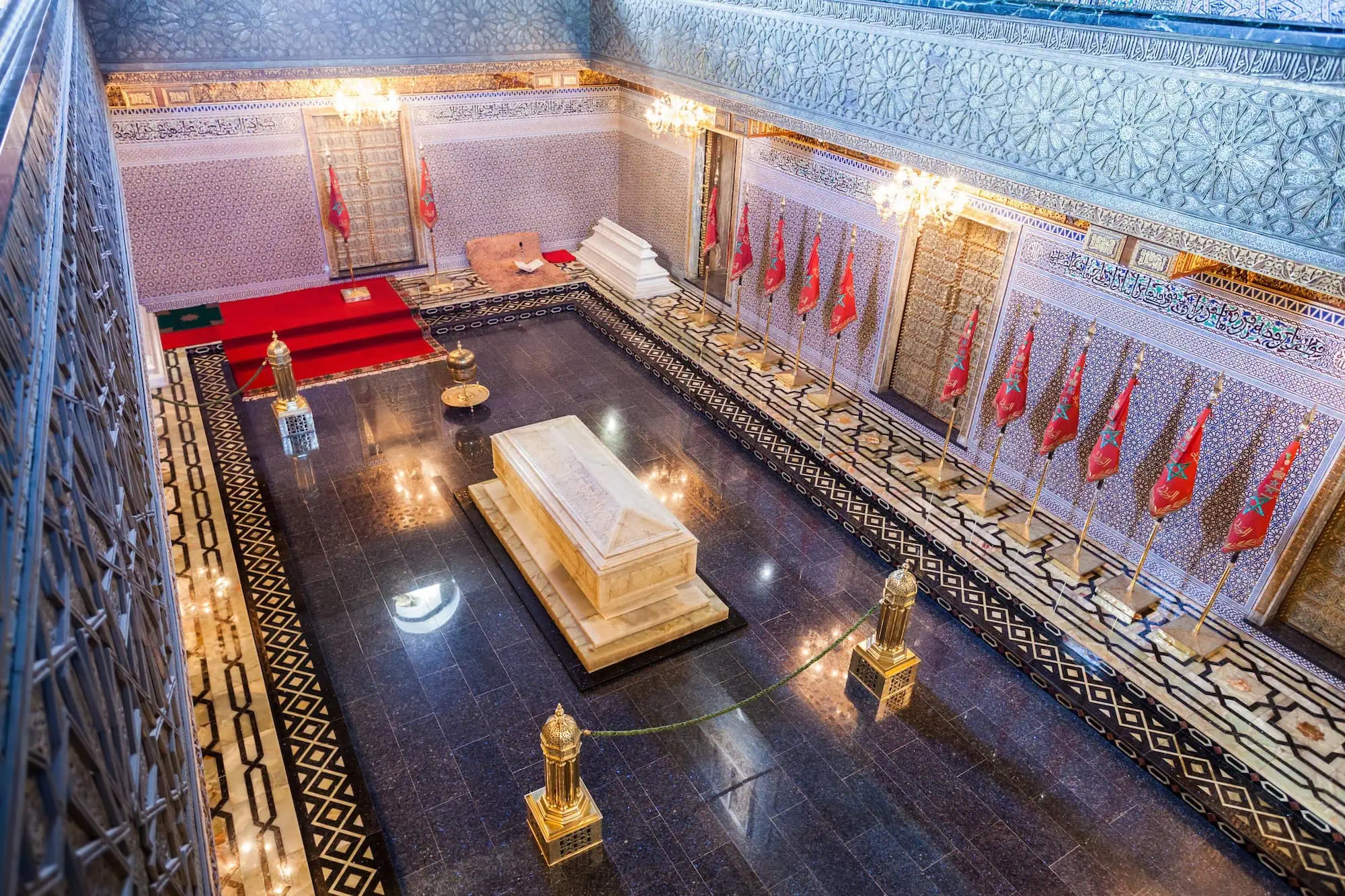 Interior of Mohammed V Mausoleum showing ornate marble tomb with Islamic geometric patterns and chandeliers