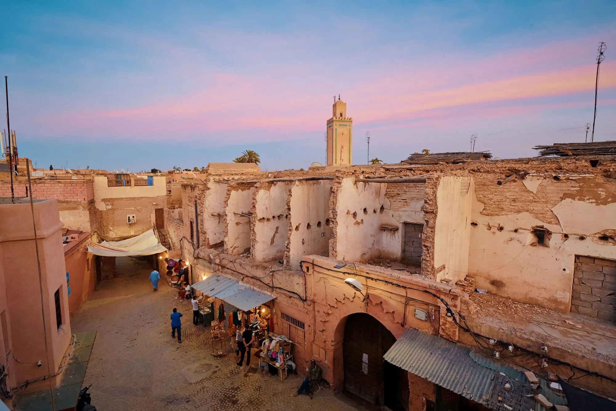 Sunset view of Marrakech's medina from a rooftop terrace showing traditional adobe buildings and minaret