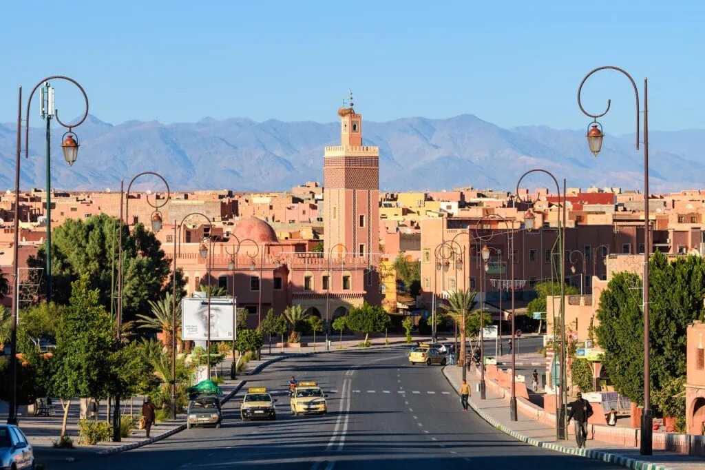 Marrakech Medina street view with mosque minaret and Atlas Mountains in the background, Marrakech