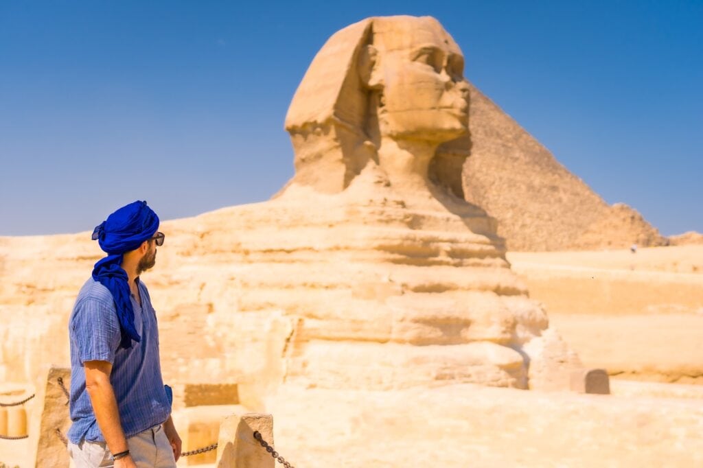 A young tourist near the Great Sphinx with the Pyramids of Giza visible in the background, Cairo