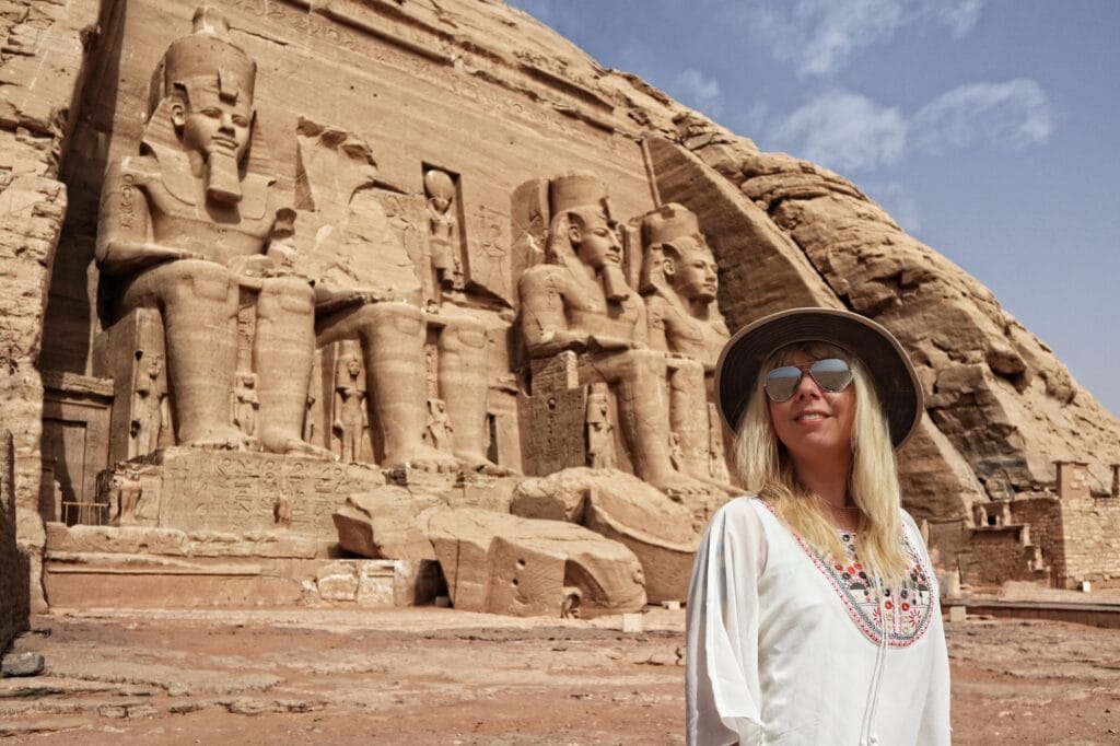 Tourist standing in front of the rock-cut temples with seated statues of Ramses II at Abu Simbel Temple, Abu Simbel